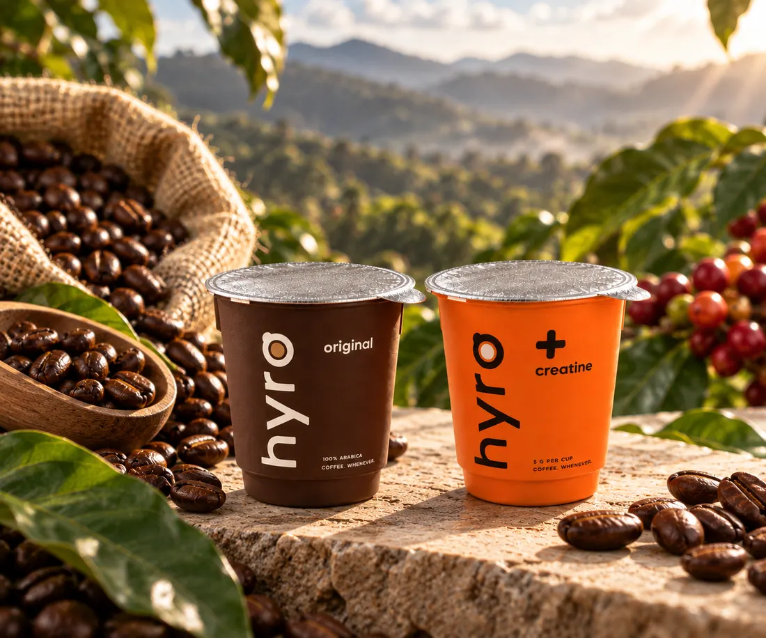 HYRO Original and + Creatine mini cups on a stone ledge above a coffee farm